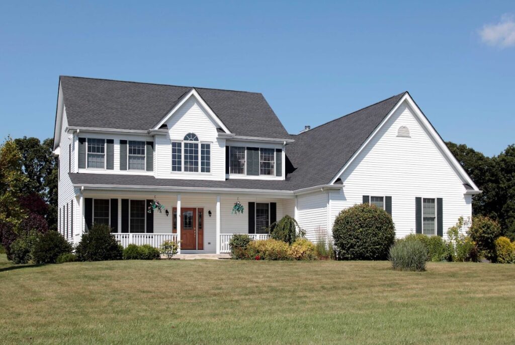 Two-story suburban house with white siding, black shutters, and a well-kept front lawn.