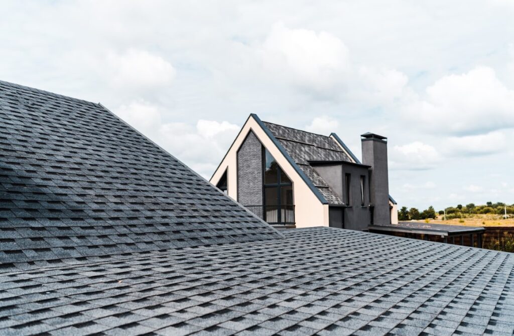 Modern home with dark gray asphalt shingle roofing and sharp gable architecture under a cloudy sky.